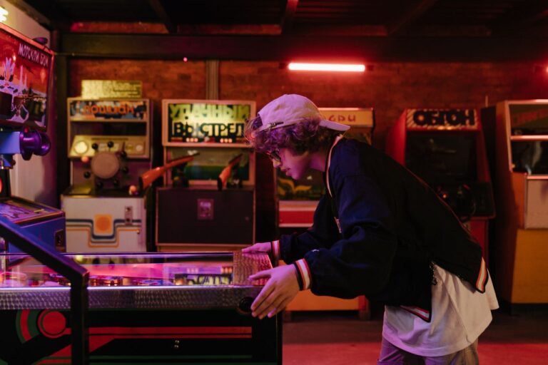 Teenager joyfully playing pinball in a nostalgic retro arcade setting.