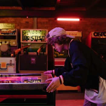 Teenager joyfully playing pinball in a nostalgic retro arcade setting.