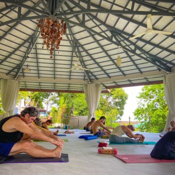 A diverse group of people practicing yoga in a tranquil open-air pavilion, focusing on health and wellness.